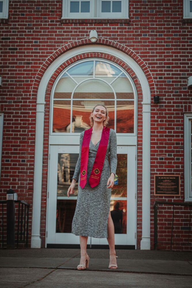 A recent graduate laughs in front of the Pelton Theatre at Willamette University
