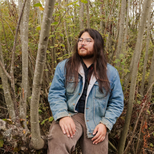 A photo of Kawika Kalama sitting in a forested area. Photo taken by Threaded Moments Photography